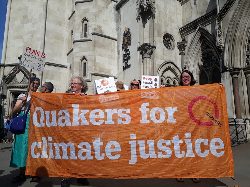 People standing outside the Royal Courts of Justice with an orange banner saying Quakers for climate justice