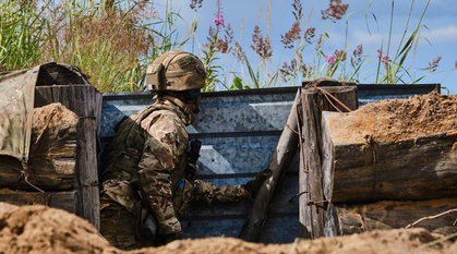 A soldier on lookout in a trench on a bright day