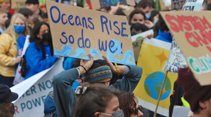 young people at a protest. Highlighted banner reads 'oceans rise and so do we' 