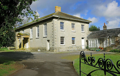 Large grey building with a pillared porch