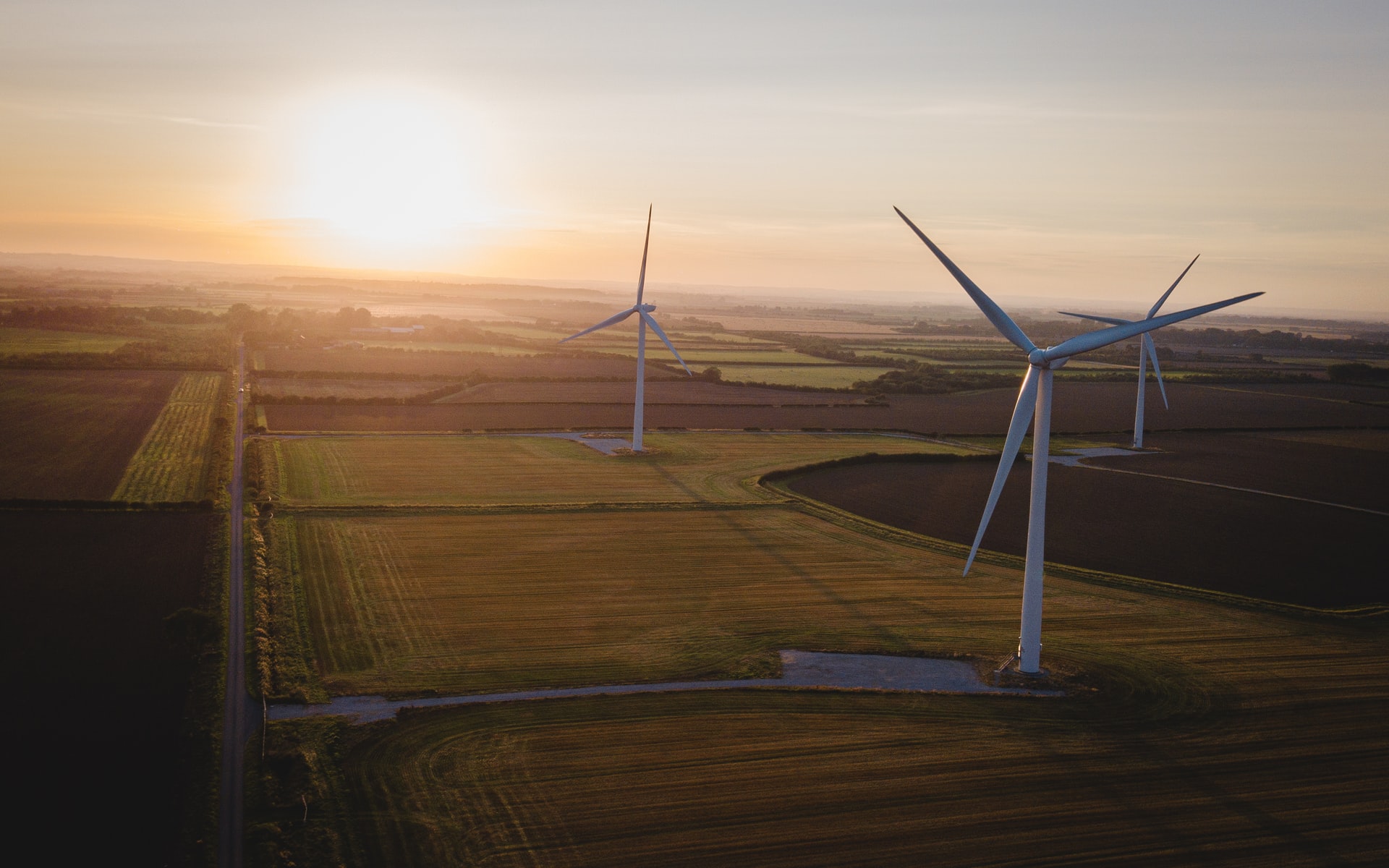 wind turbines at sunset overlooking a series of fields