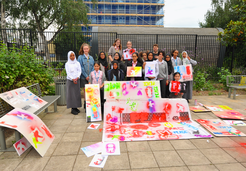 school children surrounding colourful handprinted peace banners