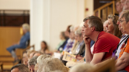 aa man leaning forward in deep concentration in a full auditorium