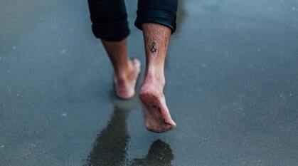 A person walking barefoot over wet sand