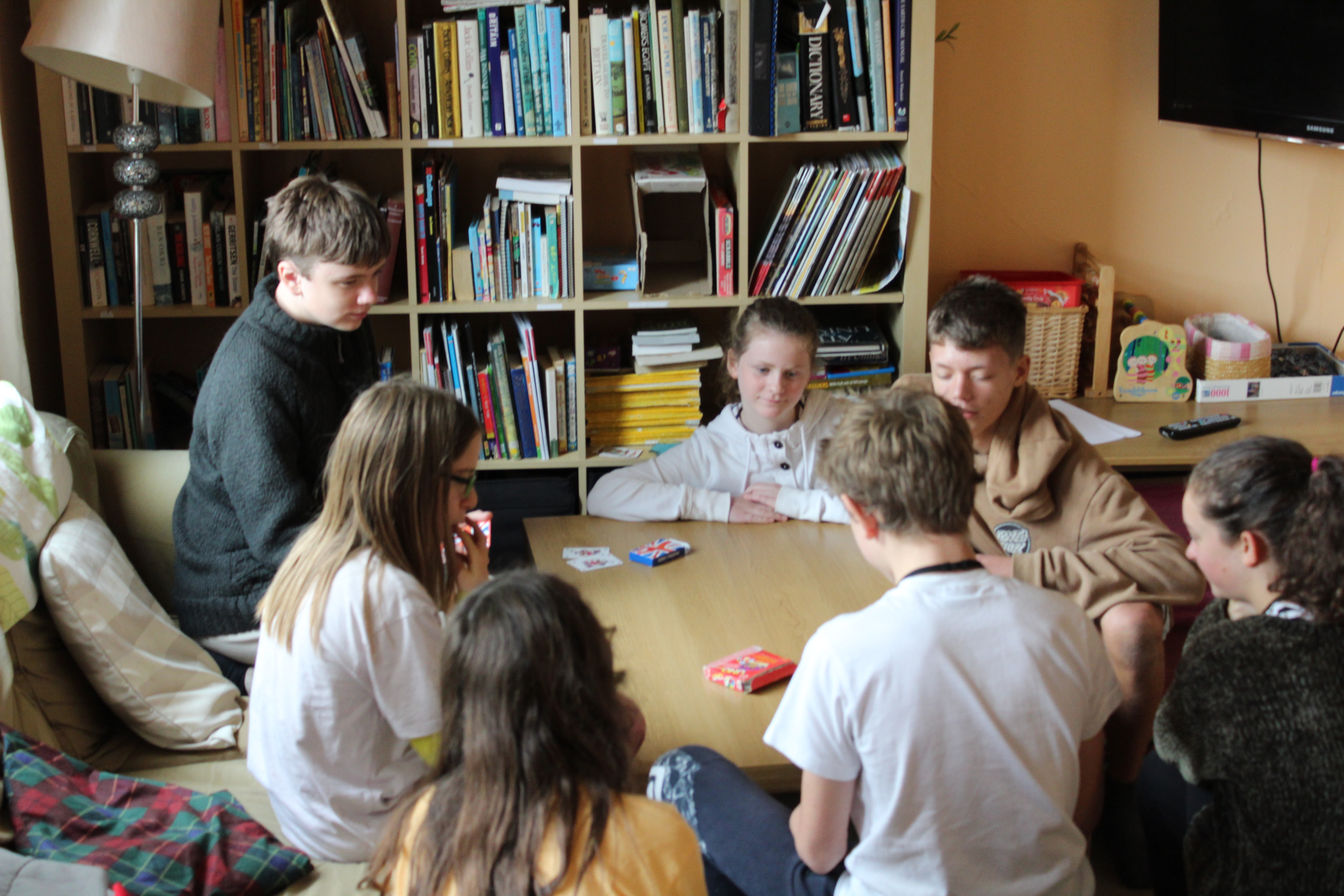 young people sitting around a table, in front of a a book case