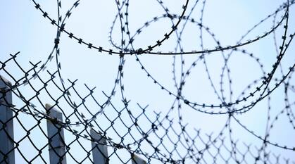 A wire fence with barbed wire around the top