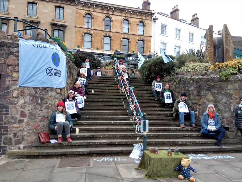 A group of people holding a vigil on some steps