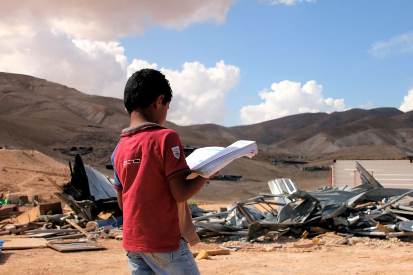 Boy reading book outside demolished building