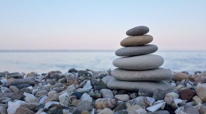 a small cairn of rounded pebbles on a pebble beach at sunset