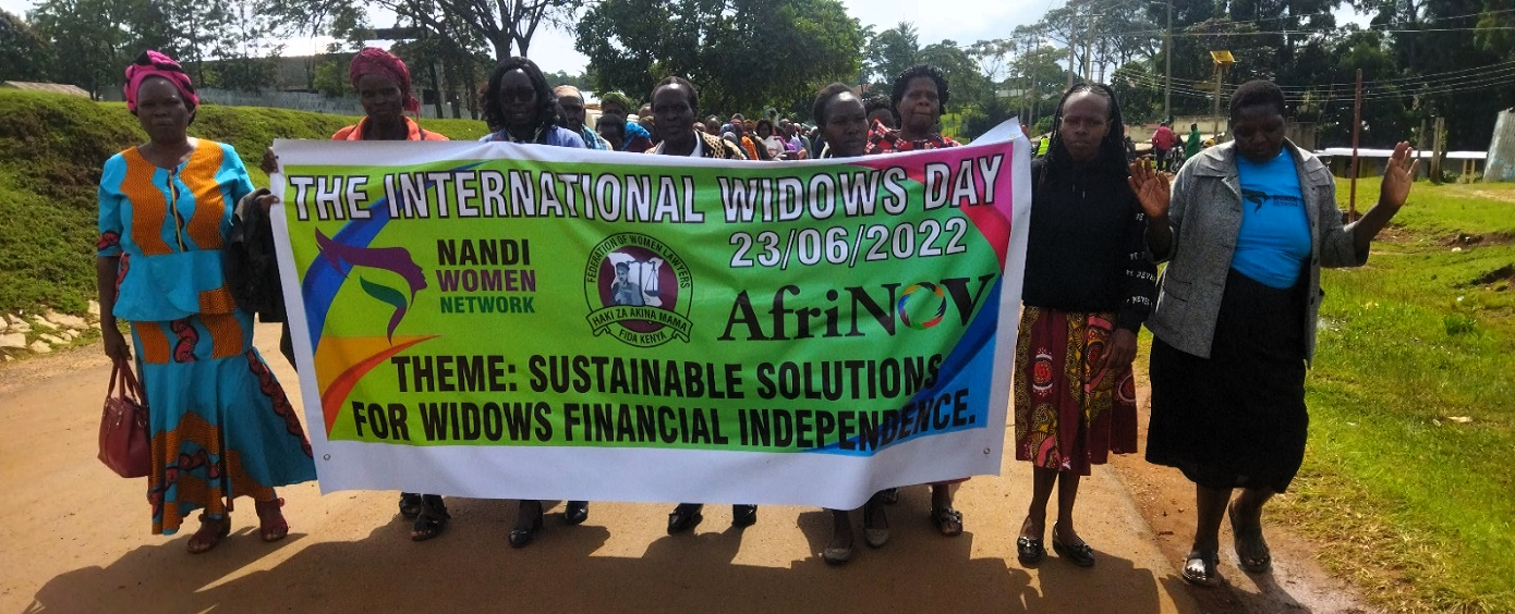 Partnering with local grassroots group to implement social justice activities. Image shows a group of women holding a banner on a march on International Widows Day