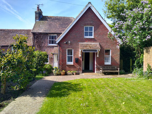 Small rural meeting house with decorative features and white doors leading to garden.