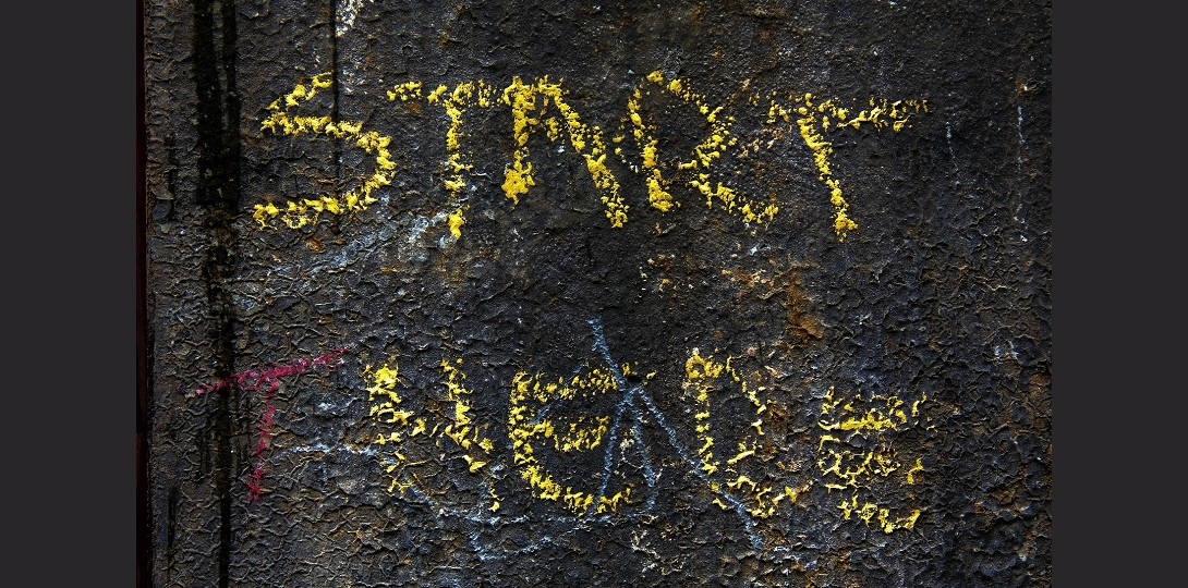 The words Start Here written in yellow chalk on tarmac