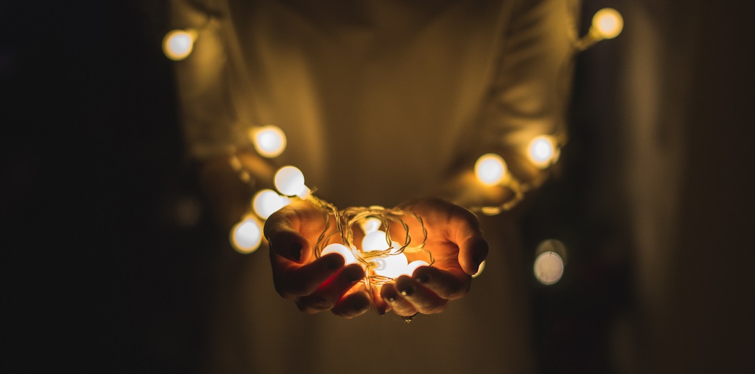 Hands cupped together holding fairy lights.
