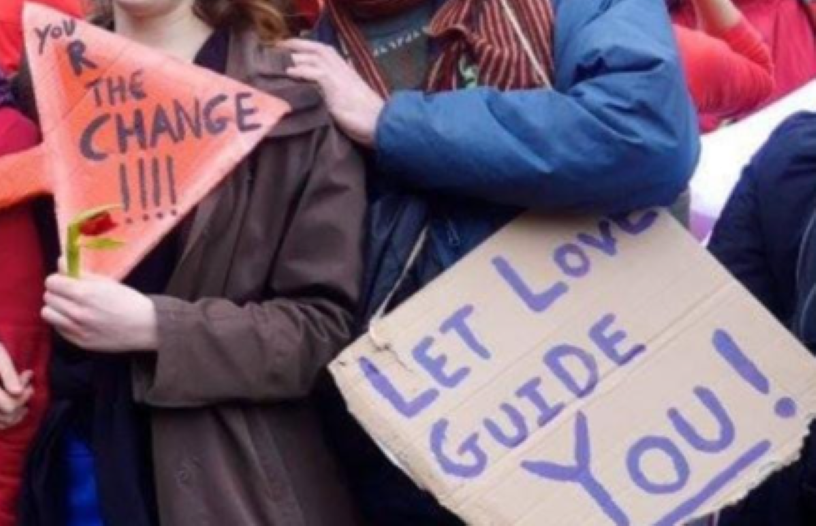 two people holding signs saying let love guide you and be the change
