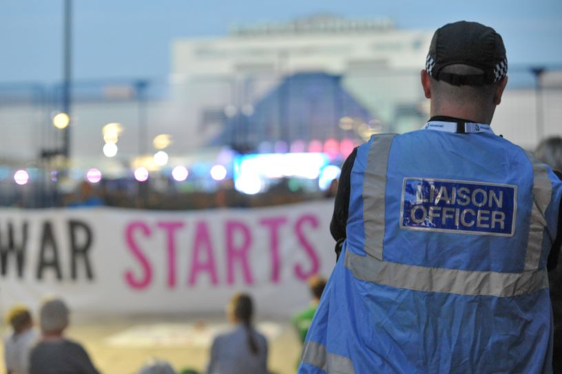 Police liaison officer in front of anti-war banner