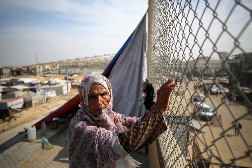 Woman in headscarf gripping mesh fence