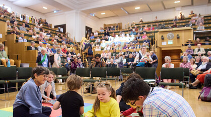 A group of children sit in the middle of the meeting room, during a session of Britain Yearly Meeting