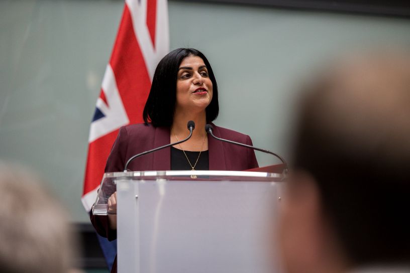 Woman at microphone in front of Union Jack