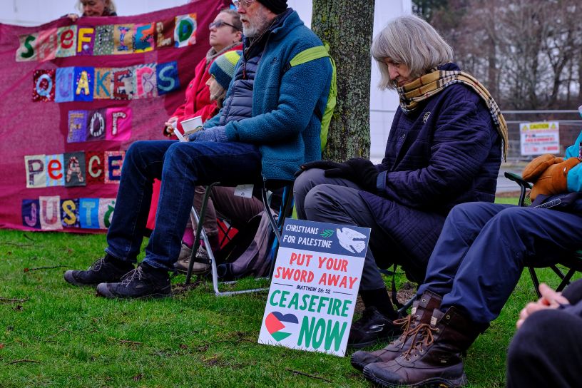 People sat on chairs with bowed heads