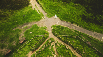 A signpost, pointing in multiple directions, against a multi-coloured sky.