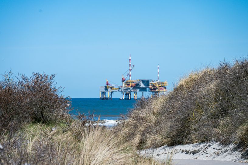 Oil rig with beach and scrub in foreground